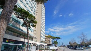 A multi-story building with a restaurant on the ground floor, a parking area, and a clear blue sky. - CV011 - Milano Marittima, sea front three-room apartment with exclusive view (Cervia)