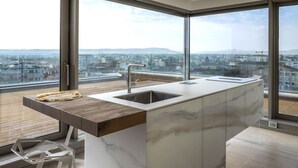 A modern kitchen with a marble countertop, a sink, and a view of the city through large windows. - Between sun and moon - Civitanova, noble apartment facing the sea (Civitanova Marche)