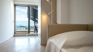 A bedroom with a bed, a large window, and a view of a cityscape. - Between sun and moon - Civitanova, noble apartment facing the sea (Civitanova Marche)