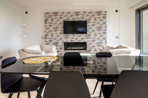 A modern dining area with a glass table, black chairs, and a sofa.