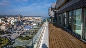 A high-rise building with a balcony overlooking a cityscape, including a prominent tower and a beach. - Between sun and moon - Civitanova, noble apartment facing the sea (Civitanova Marche)
