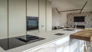 A modern kitchen with a marble countertop, built-in oven, and a flat-screen TV mounted on the wall. - Between sun and moon - Civitanova, noble apartment facing the sea (Civitanova Marche)