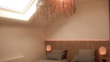 A bedroom with two beds, a skylight, and a hanging light fixture.