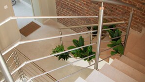 Una escalera moderna con barandillas metálicas y un muro de ladrillo.