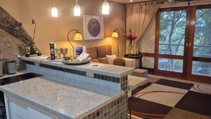 A modern bathroom with a granite countertop, a sink, and a large window with a view of trees.