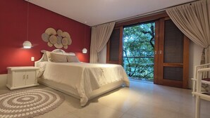 A bedroom with a bed, nightstands, a decorative wall piece, a circular rug, and a sliding glass door leading to a balcony.