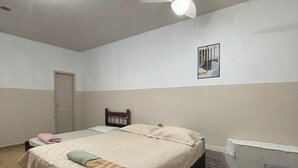 Une chambre à coucher avec un lit, un ventilateur de plafond, un radiateur et une porte.