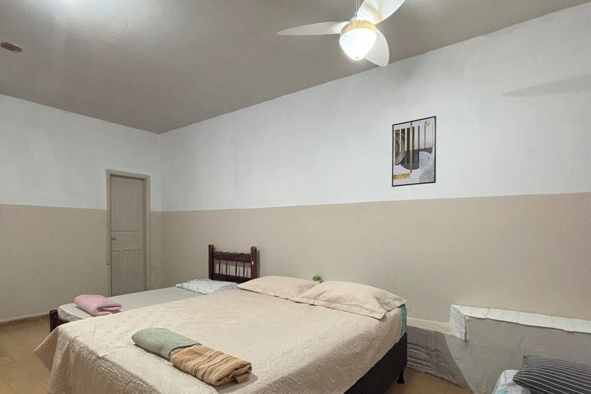 A bedroom with a bed, a ceiling fan, a radiator, and a door.