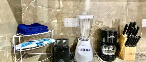 Un plan de travail de cuisine avec un mixeur, un grille-pain, une machine à café et un bloc à couteaux.