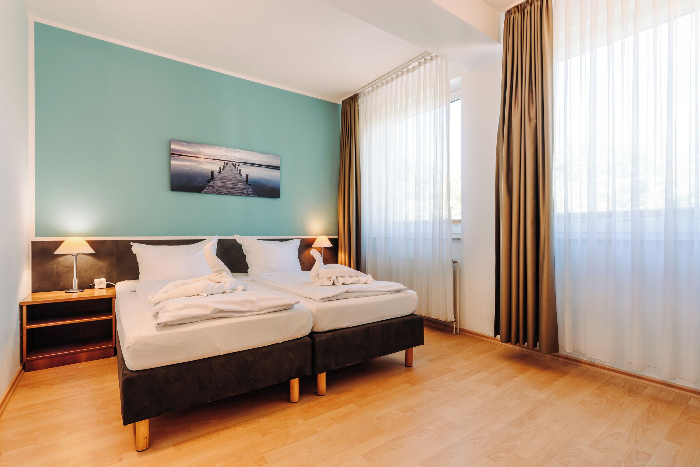 Une chambre d’hôtel avec deux lits, une table de chevet, une lampe et un tableau au mur.