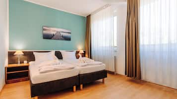 Une chambre d’hôtel avec deux lits, une table de chevet, une lampe et un tableau au mur.