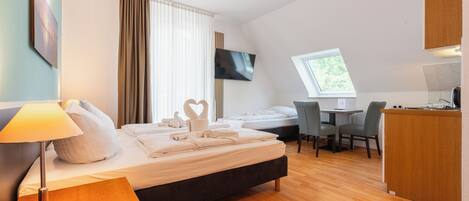 A hotel room with a bed, a desk, a chair, a TV, and a window.