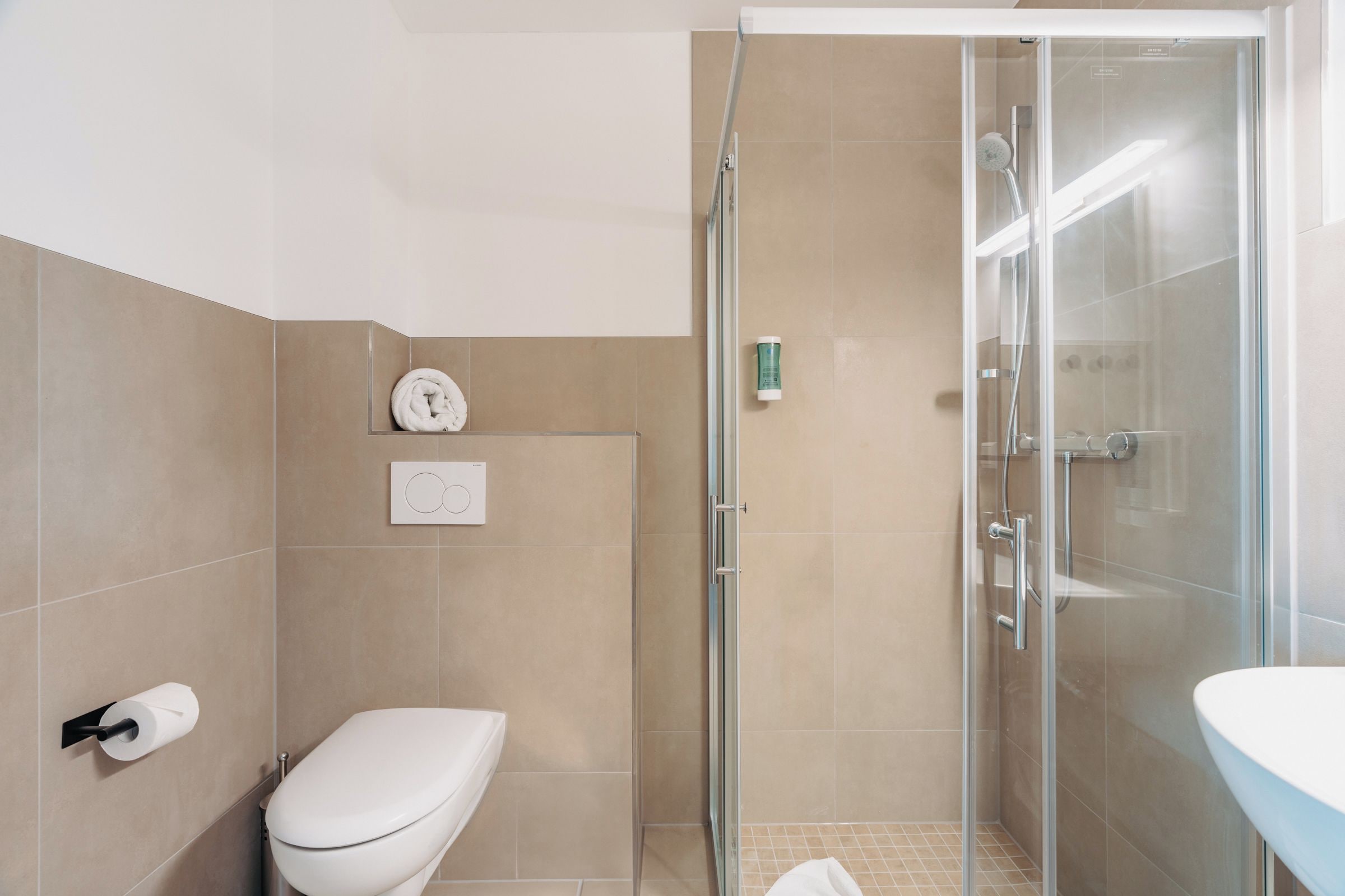Un baño moderno con inodoro, cabina de ducha de vidrio y lavamanos.