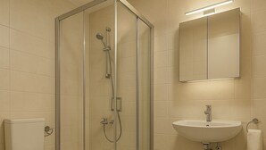 Un baño con ducha de vidrio, inodoro y lavabo con espejo.
