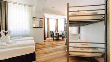 A hotel room with a bunk bed, a desk, and a dining area.