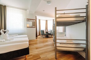 Habitació d'hotel amb lliteres, escriptori i zona de menjador.