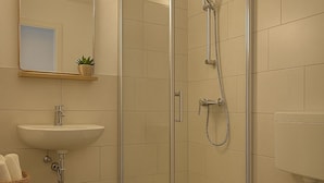 Ein modernes Badezimmer mit einer einteiligen Duschkabine, einem Waschbecken und einer Toilette.