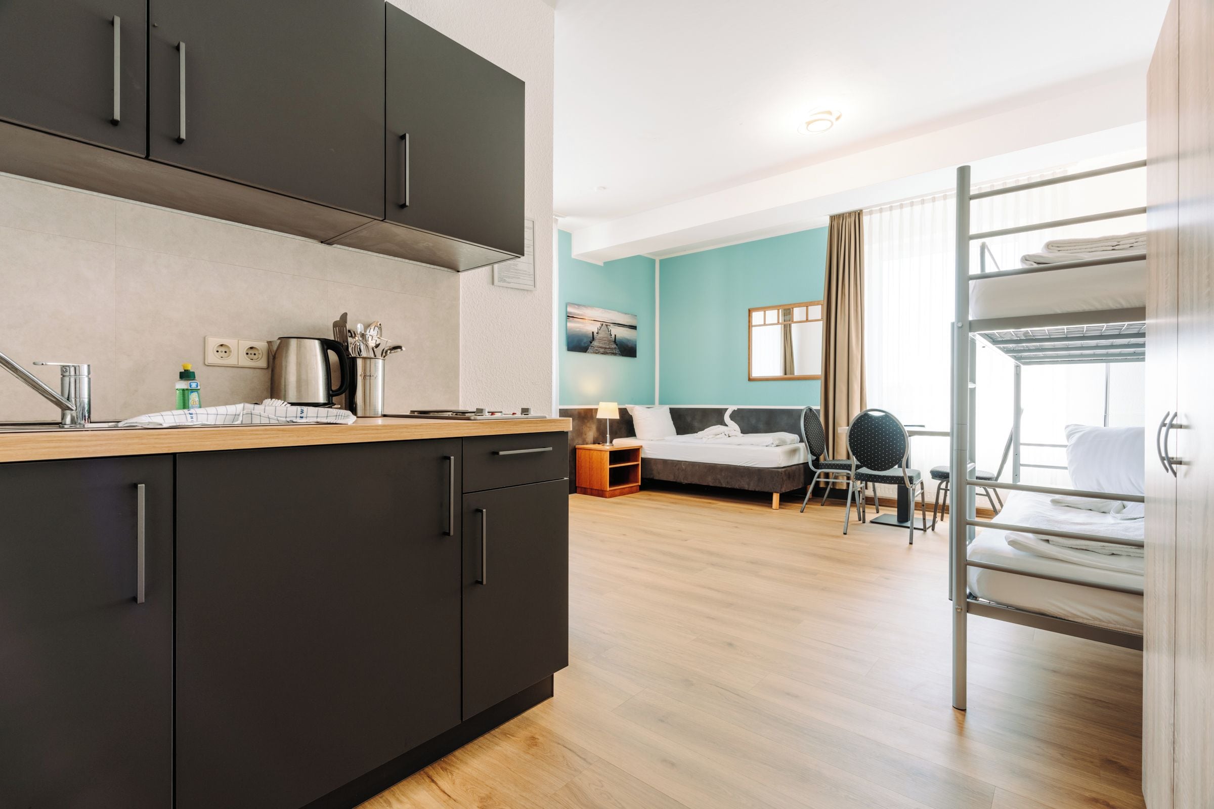 Una cocina moderna con armarios oscuros, encimera de madera y hervidor.