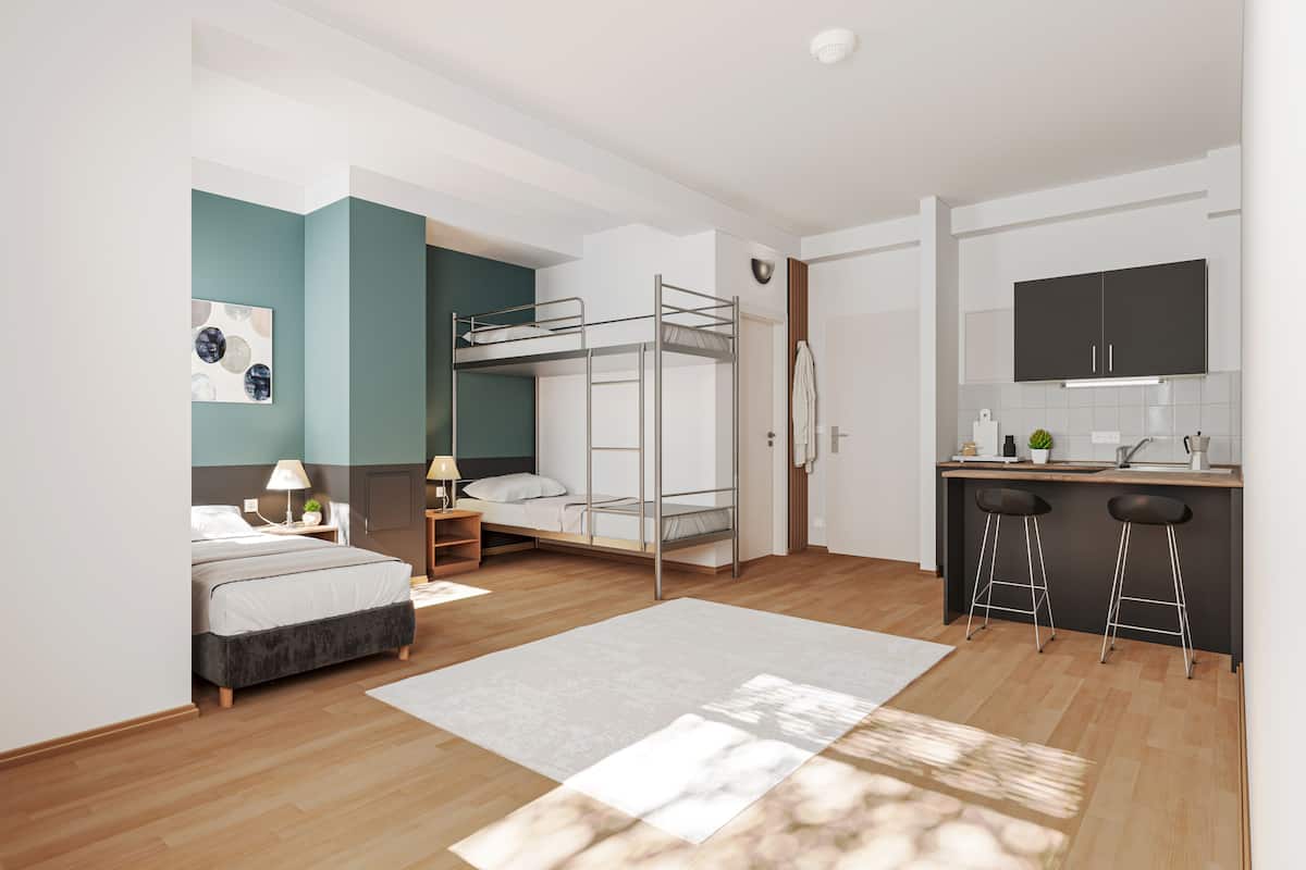 Un apartamento estudio pequeño con literas, kitchenette y un rincón comedor.