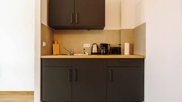A kitchen with dark cabinets, a wooden countertop, and various appliances including a coffee maker and a kettle.