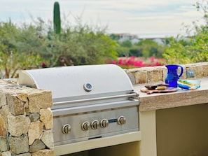 An outdoor grill with a stone wall, a blue pitcher, and a bowl on a stone countertop. - Casa Flip Flop - New, Luxury 4-bedroom (Cabo San Lucas)