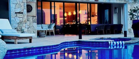 Ein Poolbereich mit Steinmauer, Liegestuhl und Essplatz mit Tisch und Stühlen.