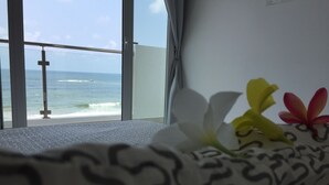 A room with a view of the ocean through large windows, a bed with a patterned bedspread, and a wall with a cross. - Wake up to panoramic ocean views from almost every room. (Dehiwala-Mount Lavinia)
