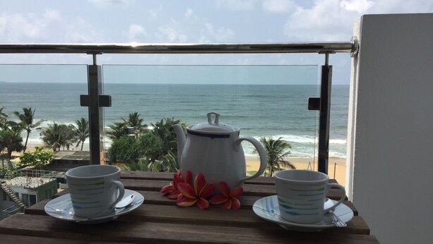 A balcony with a view of the ocean, a white teapot, and two cups on a wooden table. - Wake up to panoramic ocean views from almost every room. (Dehiwala-Mount Lavinia)