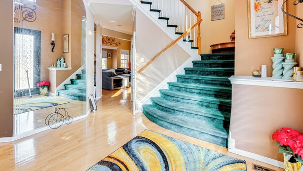 Eine Treppe mit türkisfarbenem Teppich, einer Holzhandläufe und einer weißen Wand mit einem gerahmten Zitat.