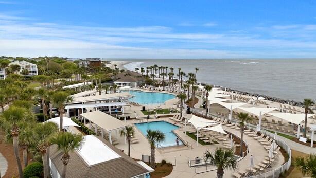 Un resort con piscina, playa y palmeras.