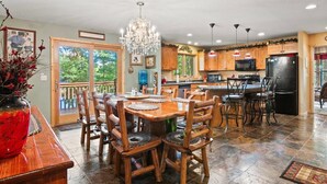 A spacious kitchen with wooden cabinets, a large island, and a chandelier.