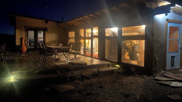 A modern house with a patio, a dining area, and large windows. - Unique and Marvelous Hideaway with the Cosmic Energy of Crestone! (Crestone)