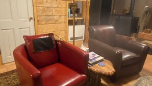 A living room with a red leather armchair, a brown leather sofa, a wooden coffee table, and a patterned rug. - Unique and Marvelous Hideaway with the Cosmic Energy of Crestone! (Crestone)
