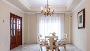 Un comedor con una araña, una puerta de madera y un cuadro en la pared.