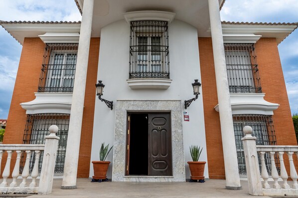A building with a large central door, two windows with iron bars, and a balcony.