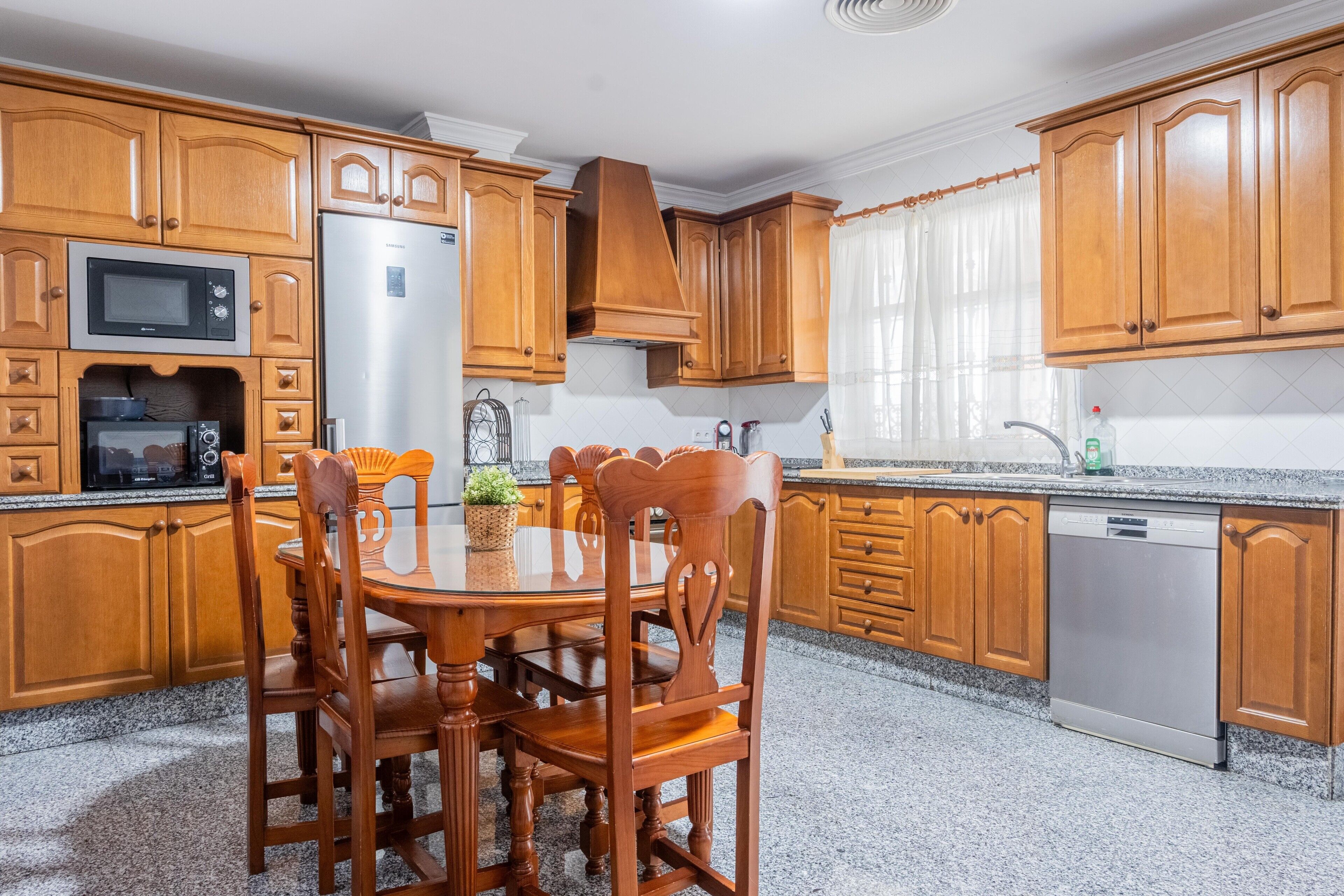 Una cocina con armarios de madera, un refrigerador de acero inoxidable, un microondas y un lavavajillas.