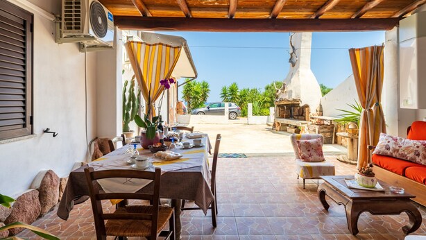 A dining area with a table set for two, a wooden ceiling, and a view of the street.
