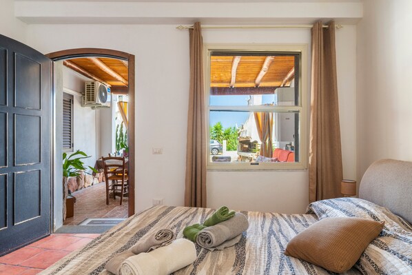 Une pièce avec un lit, une fenêtre avec des rideaux, une porte et une vue sur l’extérieur.