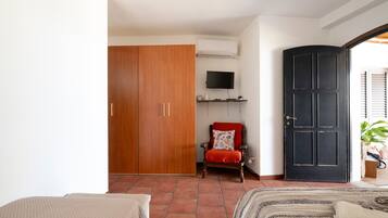 A bedroom with a wardrobe, a television, a door, and a bed.