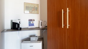 A kitchenette with a coffee maker, a kettle, and a refrigerator.