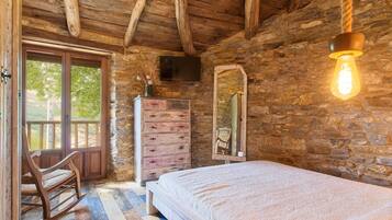 Een rustieke houten kamer met een bed, een dressoir en een schommelstoel.