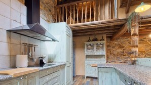 Una cocina rústica con armarios de madera, pared de piedra y una lámpara colgante.