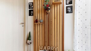 Una puerta de madera con un cartel que dice 'HAPPY PLACE', un estante con adornos y cuadros en la pared.