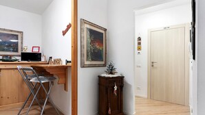 Una habitación de esquina con escritorio de madera, silla plegable, armario y puerta.