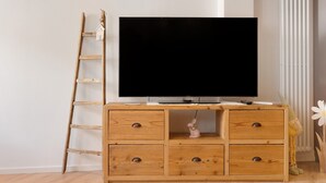 Puisesta valmistettu TV-taso, jossa on litteänäyttöinen televisio, tikkaat ja pieni koristehahmo.