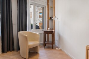 A room with a chair, a small table, a lamp, a window with curtains, and a radiator. - Studio 'Leonard Chalet House' with Balcony and Wi-Fi (Albiano)