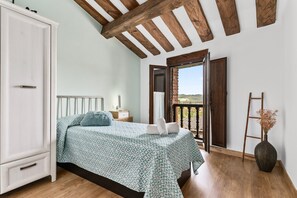 A bedroom with a bed, a wardrobe, a nightstand, a vase, and a balcony door.