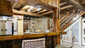 Una cocina rústica con vigas de madera, un muro de piedra y una escalera de madera.