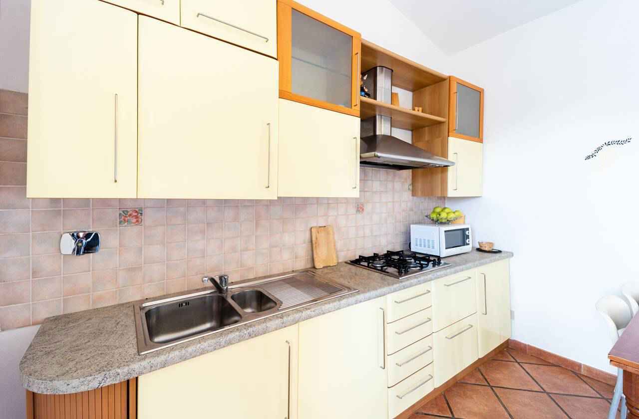 A kitchen with a sink, stove, cabinets, and a microwave.