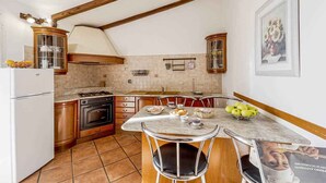 A kitchen with wooden cabinets, a stove, a refrigerator, and a dining table with chairs. - Holiday apartment with air conditioning, internet and pool (Imperia)